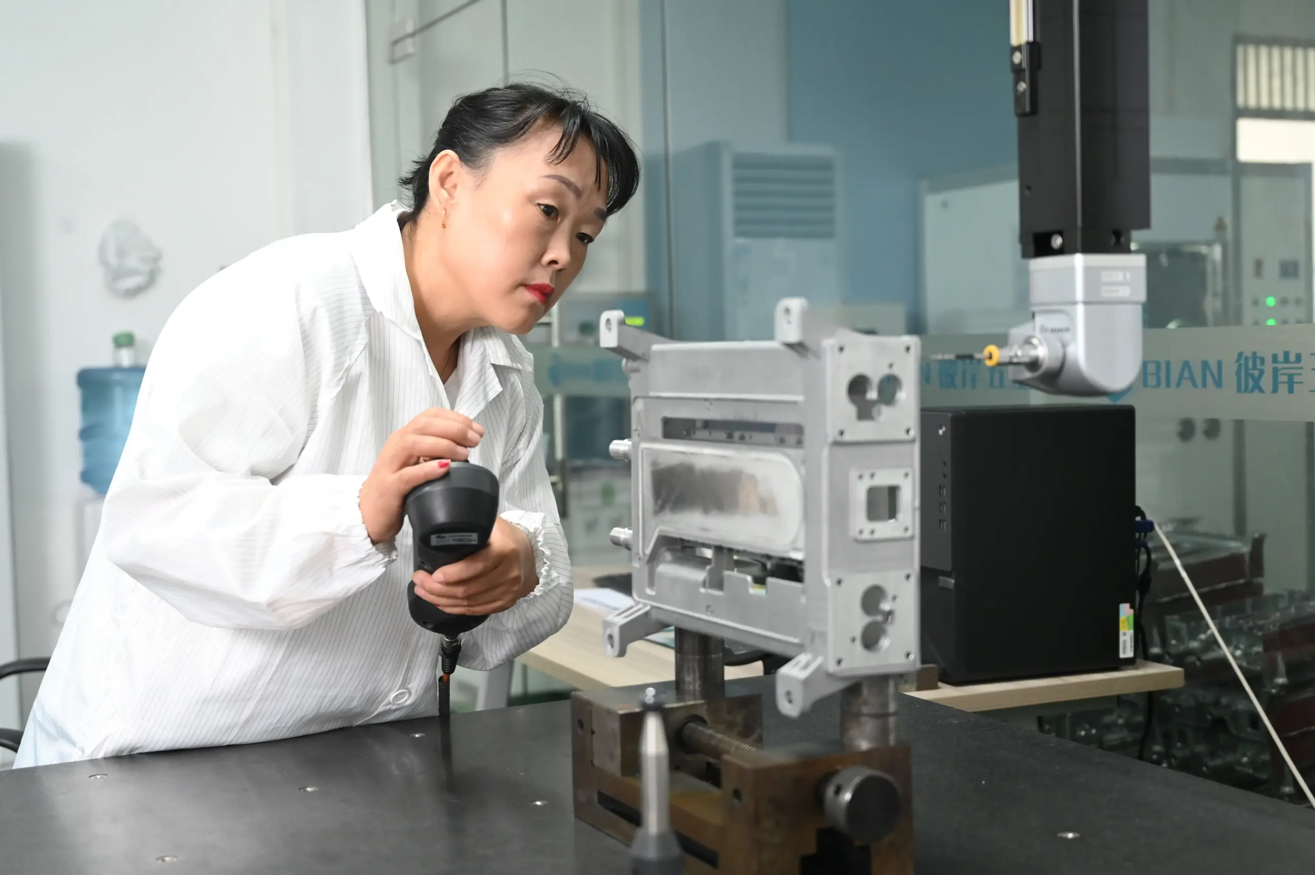 Quality engineer scanning a die cast component with a handheld scanner in a metrology lab