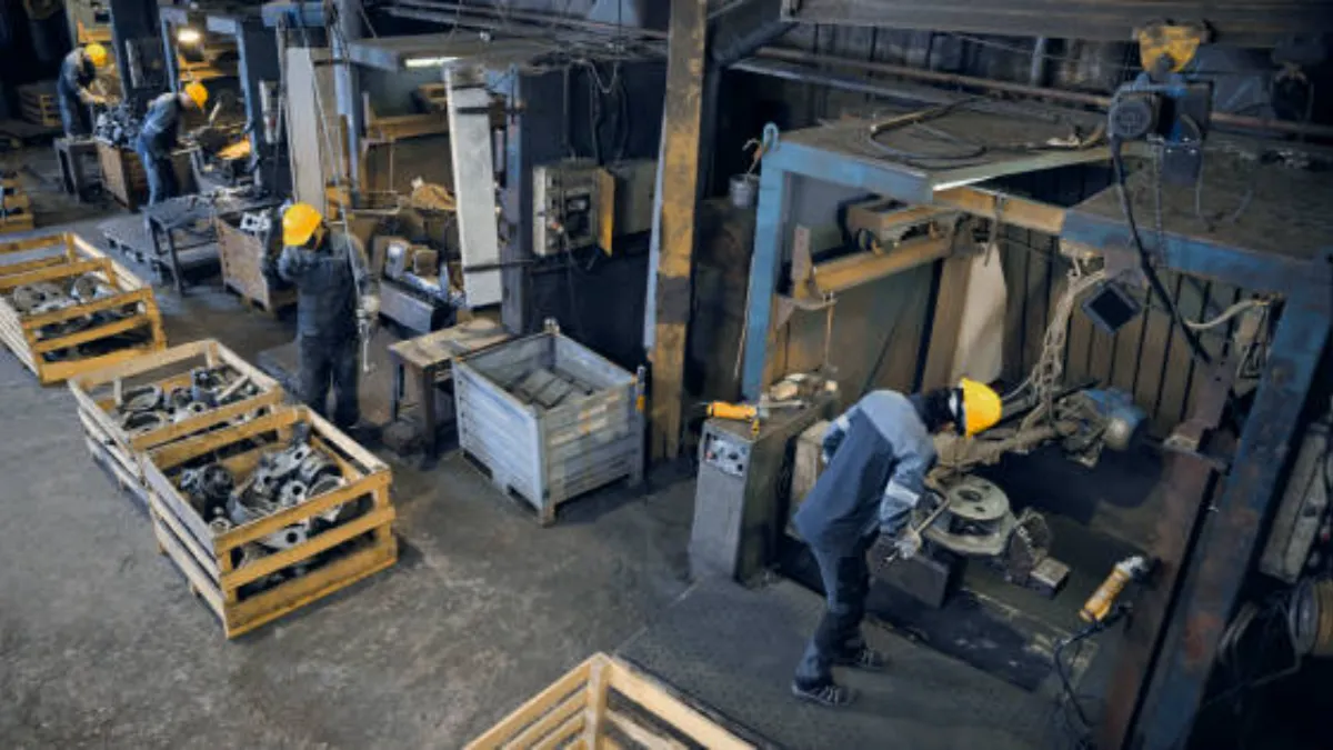 Operators at workstations handling cast aluminum parts in a production hall