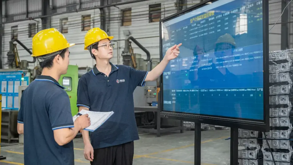 Two workers of are holding production documents and explaining the progress in factory